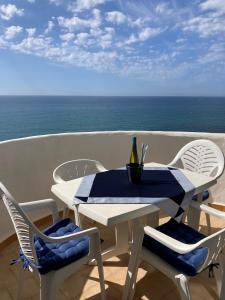 una mesa blanca y sillas en un balcón con vistas al océano en Apartamento SeaView en Sitio de Calahonda