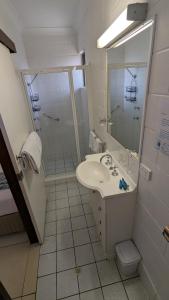 La salle de bains est pourvue d'un lavabo, d'une douche et de toilettes. dans l'établissement Moffat Beach Motel Caloundra, à Caloundra