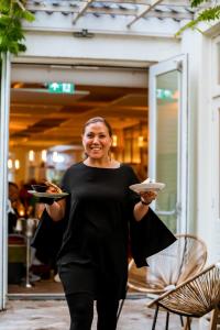 a woman is holding a plate of food at Ruim comfortabel appartement centrum Breda MET restaurant! in Breda
