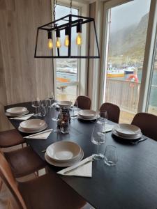 a black table with chairs and a large window at Waterfront Suite l Ballstad l Lofoten l Norway in Ballstad