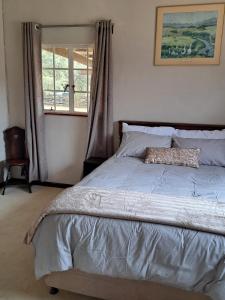 a large bed in a bedroom with a window at KASP Cottage in Underberg