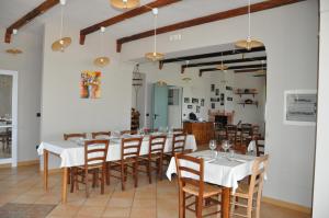 a dining room with white tables and wooden chairs at agriturismo borgo baldassarre in Cellole