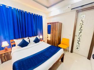 a bedroom with a bed with blue curtains and a yellow chair at Hotel Park Pride Pitampura New Delhi, Couple Friendly in New Delhi