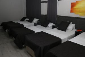 Un grupo de 4 camas en una habitación en Asus Palmiye Otel, en Adana