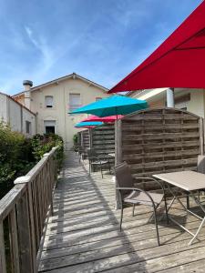 eine Terrasse mit Tischen, Stühlen und Sonnenschirmen in der Unterkunft Comme une évidence gite et chambres d'hotes in Saint-Vincent-sur-Jard