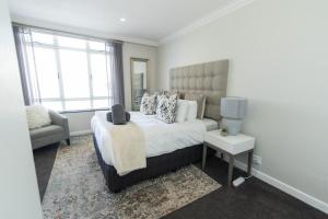 1 dormitorio con 1 cama, 1 silla y 1 ventana en Tivoli Luxury Beach Apartment en Port Elizabeth