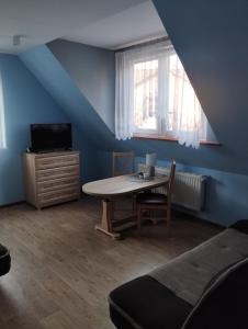 ein blaues Zimmer mit einem Tisch, einem Bett und einem Fenster in der Unterkunft Pokoje gościnne u Steni in Kudowa-Zdrój