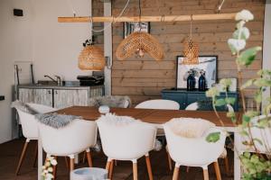 a dining room with a wooden table and white chairs at SOONWALD Studio mit Terrasse & Whirlpool in Stromberg