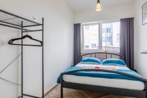 Un dormitorio con una cama con almohadas azules y una ventana en EVA-Modern 2 bedroom apartment seaside Oostende en Ostende