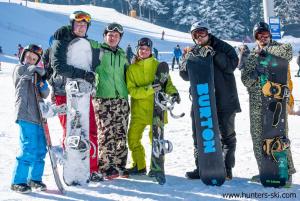 a group of people standing in the snow holding snowboards at PM Services Royal Plaza Apartments in Borovets