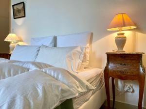 Una cama con sábanas blancas y una lámpara en una mesita de noche. en Chateau la Bainerie, en Tiercé