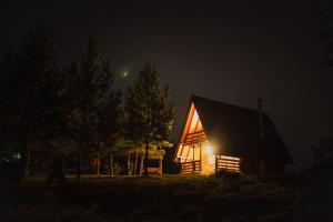 a large wooden house with a lit up facade at night at Ranč Crna stina in Livno