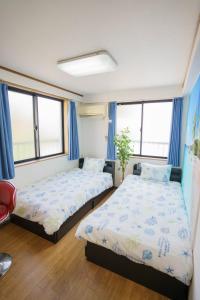 Duas camas num quarto com cortinas azuis e janelas em BURan House em Tóquio
