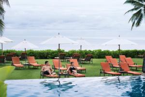 Dos personas sentadas en sillas junto a una piscina en Sheraton Hua Hin Resort & Spa en Cha Am