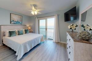 um quarto com uma cama, uma televisão e uma varanda em Sand Castle em Kure Beach