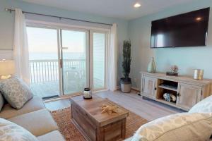 a living room with a couch and a tv at Sand Castle in Kure Beach +42 photos