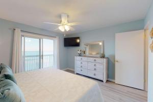 um quarto com uma ventoinha de tecto e uma cómoda com um espelho em Sand Castle em Kure Beach