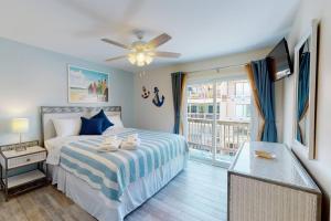 a bedroom with a bed with a ceiling fan and a window at Easy Breezy in Carolina Beach +40 photos
