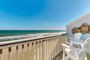 a balcony with two white chairs and the ocean at Saltwater Kure in Kure Beach