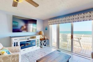 a living room with a fireplace and a view of the ocean at Saltwater Kure in Kure Beach
