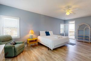 ein Schlafzimmer mit einem Bett, einem Stuhl und einem Sofa in der Unterkunft Blue Heron Nest in Carolina Beach