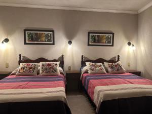 um quarto com duas camas e duas fotografias na parede em Casa Tecolote em Guanajuato