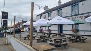 un grupo de mesas de picnic con sombrillas frente a un edificio en Vale of York restaurant and rooms, en Thirsk