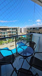 Un balcón con mesa y sillas y una piscina. en Mana Beach Resort By Smart Stays, en Porto de Galinhas