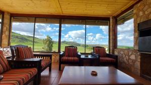 a room with chairs and tables and a large window at Berryfields in Dullstroom