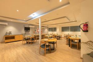 a restaurant with wooden tables and chairs and a kitchen at Hotel GT at Delhi Airport in New Delhi