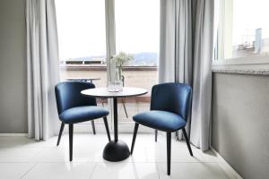 a table and two blue chairs in a room with a window at numa I Turi Apartments in Zurich