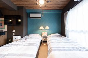 2 camas en una habitación con paredes azules en Few Days Condominium 205, en Jozankei