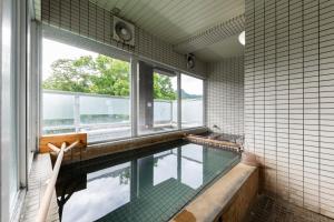 a swimming pool in a bathroom with a window at Few Days Condominium 205 in Jozankei