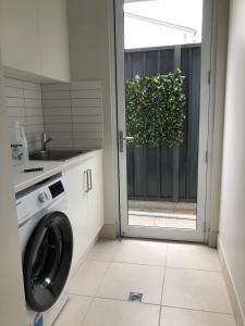 a laundry room with a washing machine and a window at Beaufort House in Port Noarlunga