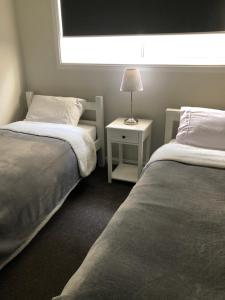 a bedroom with two beds and a table with a lamp at Beaufort House in Port Noarlunga