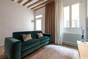 a living room with a green couch and two windows at MURANO Place - MISTRO House in Murano