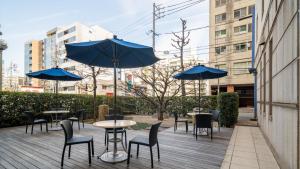 un patio con mesas, sillas y sombrillas azules en Meitetsu Inn Nagoya Kanayama en Nagoya