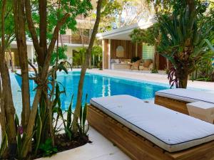 a swimming pool with two chaise lounges and trees at ☆ Location & Comfort ☆ Jacuzzi ☆ Luxury Condo in Tulum