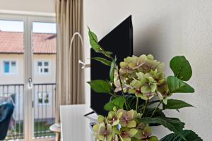 Un jarrón con flores en una habitación con ventana. en Terralpin Apartments - 27qm, en Bruckmühl