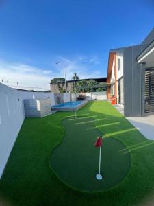 un campo de golf con putting green y bandera roja en Armaya Pool Villa Klang en Klang