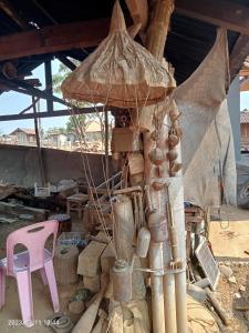 a wooden tower with pots and a pink chair at Ban Na Pia - Family Home stay in Muang Phônsavan