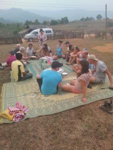 a group of people sitting on a blanket on the ground at Ban Na Pia - Family Home stay in Muang Phônsavan