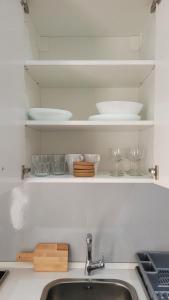 a kitchen sink with plates and bowls on shelves at Guest house Teatinos in Málaga