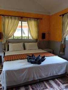 - une chambre avec un grand lit blanc et une fenêtre dans l'établissement Ban Elephant Blanc Bungalow, à Kata Beach