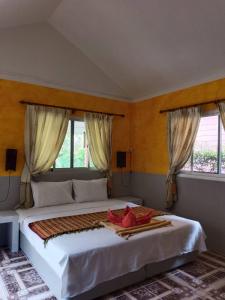 a bedroom with a large white bed with windows at Ban Elephant Blanc Bungalow in Kata Beach