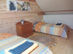 een slaapkamer met 2 bedden en een houten muur bij Le Jardin Enchanteur, chaleureuse maison d'hôtes calme et accueillante in Lopérec