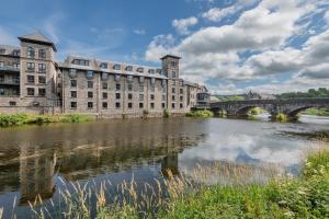 un gran edificio junto a un río con un puente en The Riverside, en Kendal