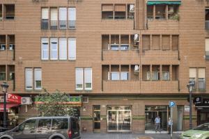 a tall brick building with a car parked in front of it at Macflats Ciudad de las Ciencias in Valencia
