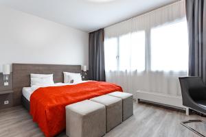 a bedroom with a bed with a red blanket and a tv at Art & Business Hotel in Nürnberg