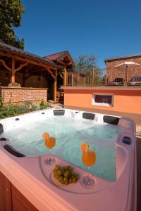 a hot tub with two wine glasses and fruit in it at Holiday&wellness house Grofica in Daruvar